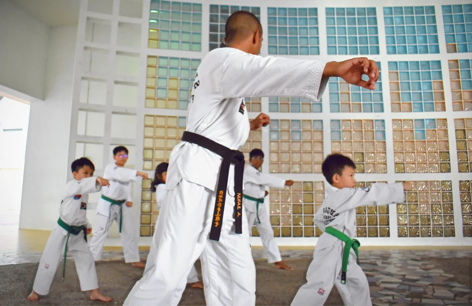 A coach leading students through Taekwondo patterns